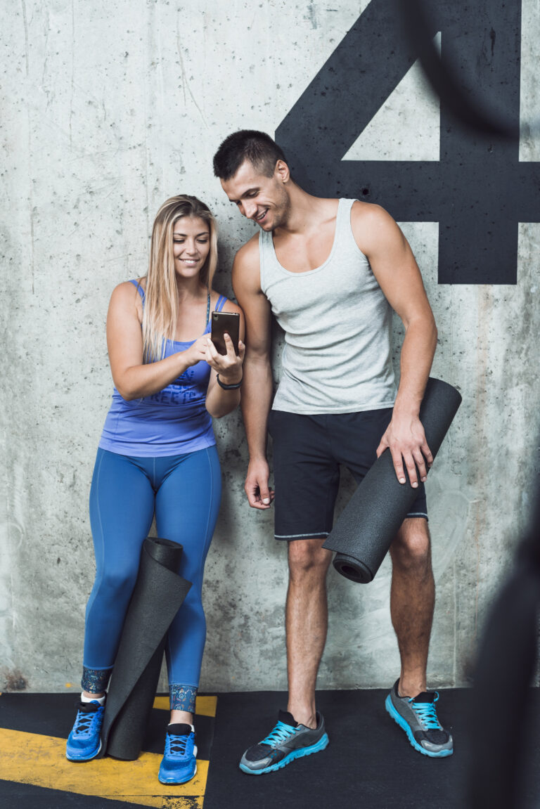 happy-man-woman-looking-cellphone-gym